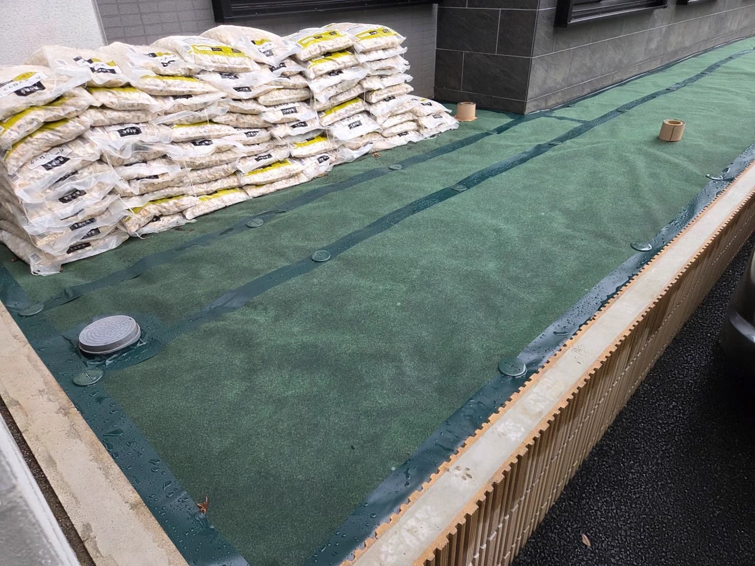 防草シートを敷き砕石袋を積んだ施工中の敷地